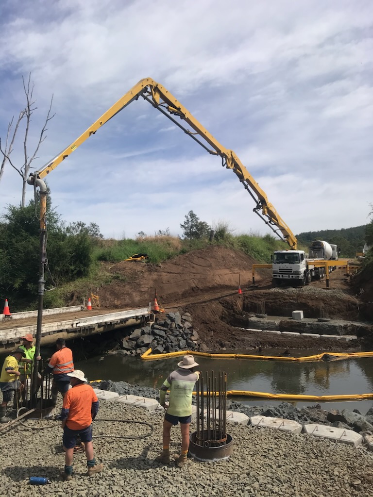 Boom pump pouring concrete for bridge foundations along a waterway in regional NSW